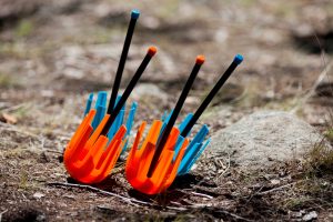 A pair of safe orange lawn darts next to a pair of safe blue lawn darts.