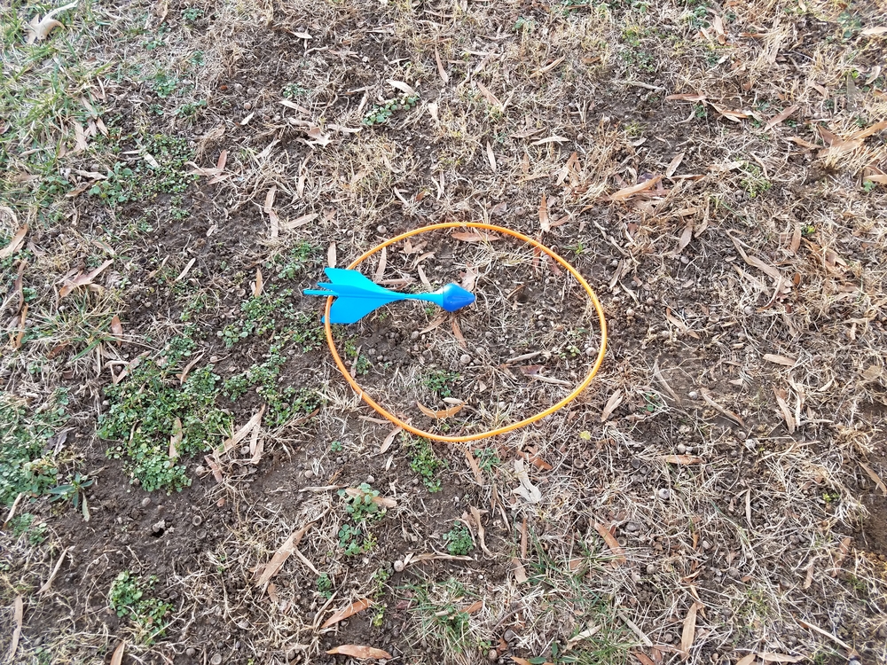 A blue lawn dart in a circle on the ground.