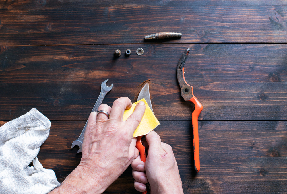 Someone's hands cleaning garden scissors on a table.