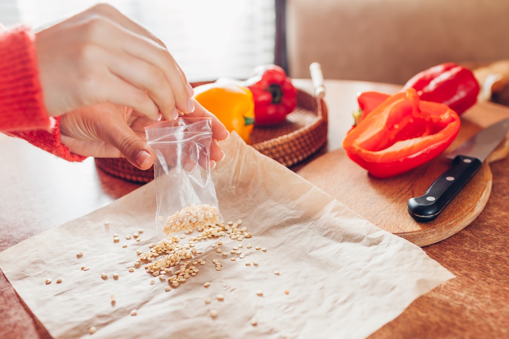 A woman saving seeds in a plastic bag.
