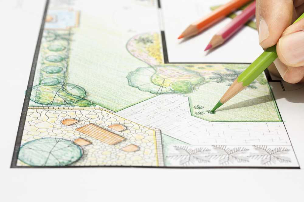 A closeup of someone drawing plans for a garden with colored pencils.