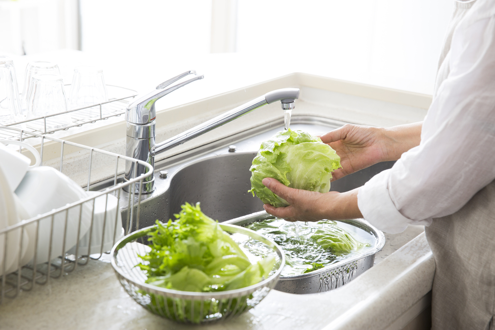 Someone washing lettuce in their sink.