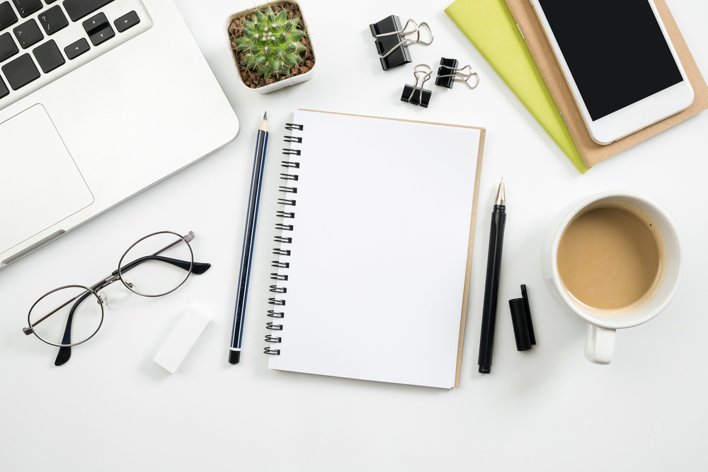 An overhead view of office supplies, laptop, coffee, and other things.